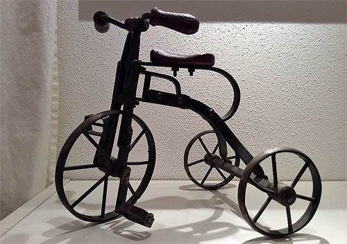 Historischer Dreirad-Drahtesel als Deko auf einem weißen Regal