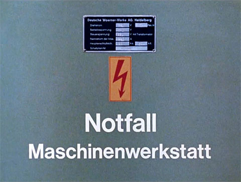 Titelbild des Kurzfilmes „Notfall Maschinenwerkstatt" mit der grauen Tür eines Schaltschrankes mit Typenzeichen und Hochspannungszeichen, Teil 3 aus der Erste-Hilfe-Serie "Rette mich, wer kann"