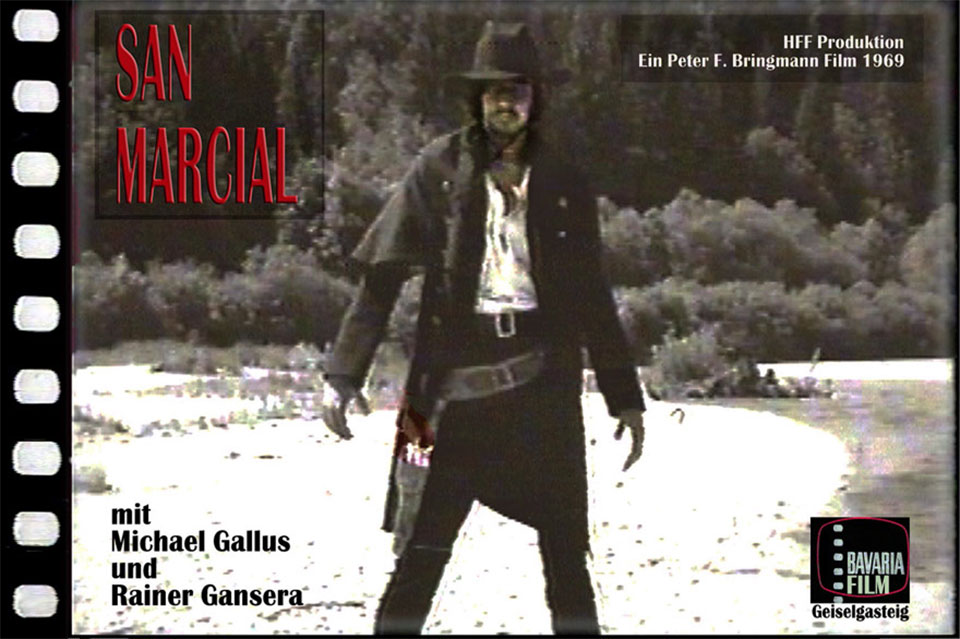 Filmtitel vom HFF-Western "San Marcial“ mit Michael Gallus als klassischer Revolverheld mit schwarzem Westernhut und langem, schwarzem Mantel und beiden Händen in typischer Duell-Haltung kurz vorm Ziehen seines tief gebundenen Revolver im Revolvergurt