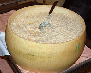 Käse-Risotto zubereitet in einem Grana-Padano-Käselaib in der Osteri Portici in Morcote (Kanton Tessin, Schweiz)