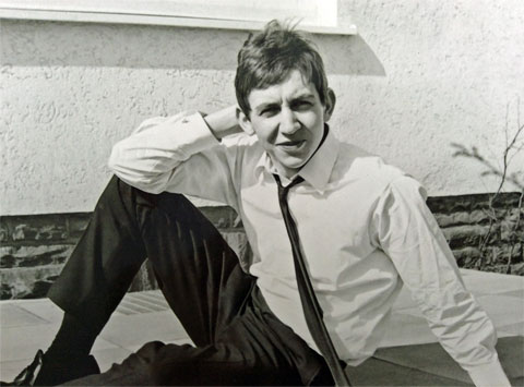 Michael Gallus als Jugendlicher auf dem Terrassenboden sitzend zu Hause mit weißem Hemd, schwarzer Krawatte, Anzugshose und schwarzen Ausgehschuhen