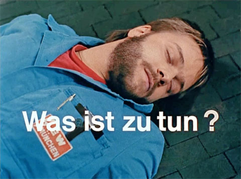 Thomas Knitter als Elektrounfall-Opfer am Boden liegend und darüber die Film-Schrift „Was ist zu tun ?"