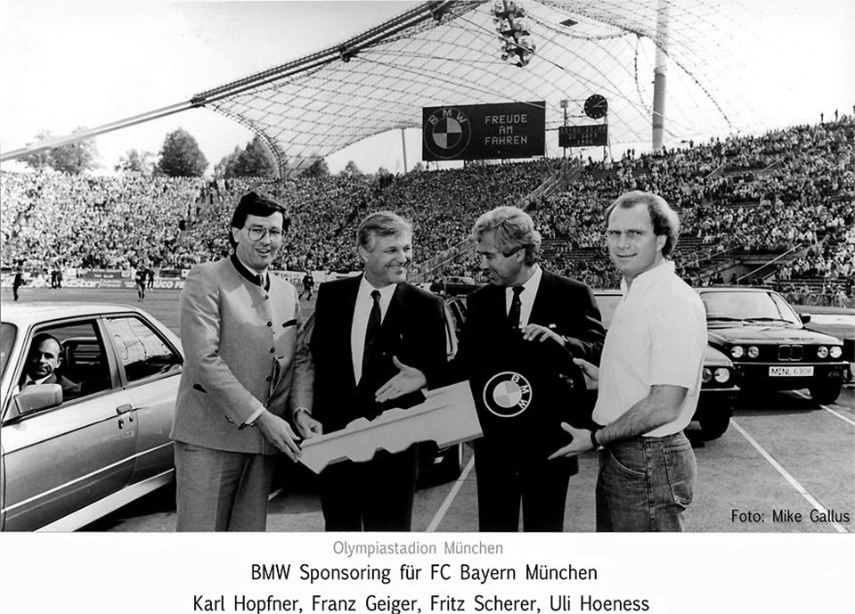 Pressebild zum BMW Sponsoring bei einem Fußballspiel im mit Zuschauern gefüllten Olympiastadion München für den FC Bayern München anlässlich der Vorstellung des neuen BMW M3 mit Karl Hopfner, Franz Geiger, Fritz Scherer und Uli Hoeness, die einen großen BMW-Autoschlüssel gemeinsam halten